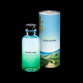 Louis Vuitton Pacific Chill fragrance bottle in a gradient of light blue to green, standing next to its cylindrical packaging sleeve featuring a tropical beach landscape, set against a solid black background.